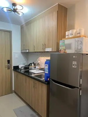 a kitchen with a stainless steel refrigerator and wooden cabinets at Cozy Vibes near MOA & NAIA AIRPORT with NETFLIX,MINIVIDEOKE,BOARDGAMES-DUXE4 in Manila