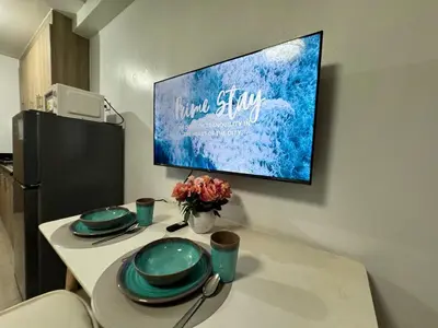 a table with green plates and a tv on a wall at 726 Shore 2 Residences near SM MOA & IKEA by Prime Stay in Manila