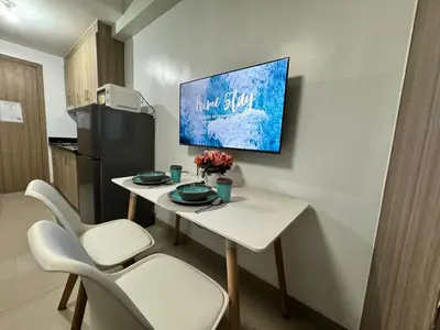 a kitchen with a table with chairs and a tv on the wall at 726 Shore 2 Residences near SM MOA & IKEA by Prime Stay in Manila