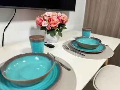 a table with two plates and a vase with flowers at 726 Shore 2 Residences near SM MOA & IKEA by Prime Stay in Manila
