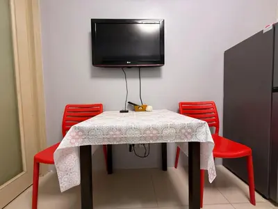 a table with red chairs and a tv on a wall at Sea Residences Briella's Staycation in Manila