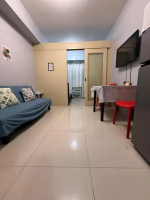 a room with a bed and a table and a television at Sea Residences Briella's Staycation in Manila