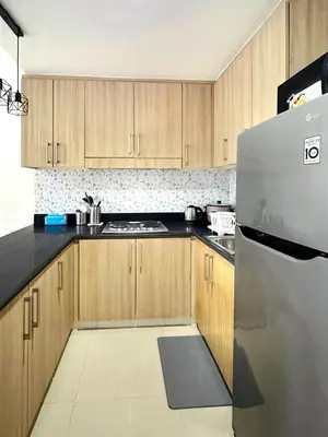a kitchen with wooden cabinets and a stainless steel refrigerator at Shore Residences 2 Bedroom Near NAIA Airport and MOA in Manila