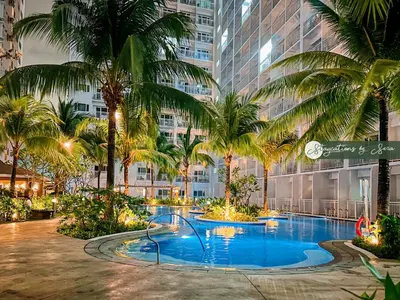 a large pool with palm trees in a building at Shore Residences 2 Bedroom Near NAIA Airport and MOA in Manila