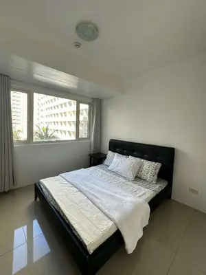 a bedroom with a large bed with a window at Shore Residences 2 Bedroom Near NAIA Airport and MOA in Manila