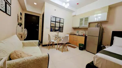 a living room with a couch and a kitchen at J&M Cozy Retreat - McKinley Hill, BGC in Manila