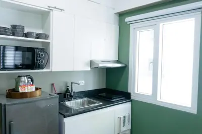 a kitchen with white cabinets and a sink and a window at The Beacon Condo T2-Studio in Manila