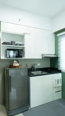 a kitchen with white cabinets and a stainless steel refrigerator at The Beacon Condo T2-Studio in Manila