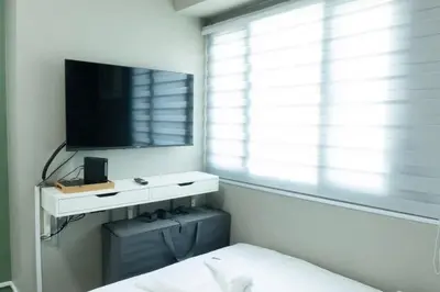 a bedroom with a tv and a bed and a window at The Beacon Condo T2-Studio in Manila