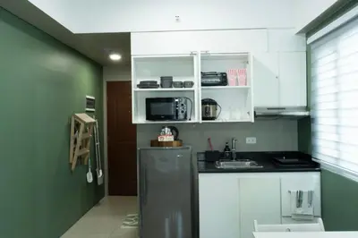 a kitchen with green walls and white cabinets and a refrigerator at The Beacon Condo T2-Studio in Manila