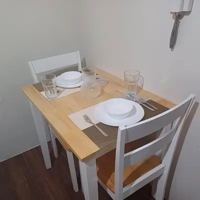 a wooden table with two plates and glasses on it at Urban Space 1BR with Balcony in Manila