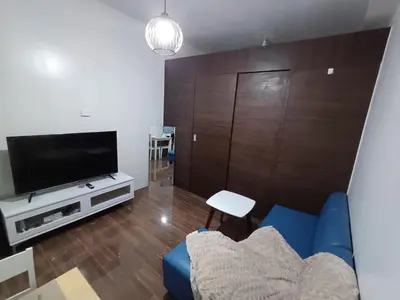 a living room with a blue couch and a television at Urban Space 1BR with Balcony in Manila