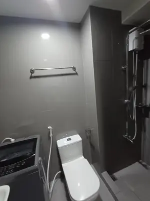 a bathroom with a white toilet and a shower at Urban Space 1BR with Balcony in Manila