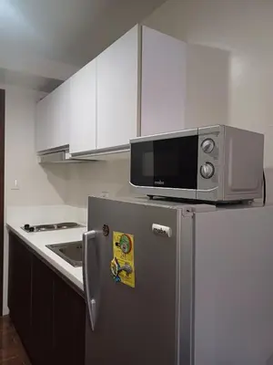 a microwave on top of a refrigerator in a kitchen at Urban Space 1BR with Balcony in Manila