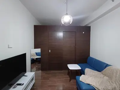 a living room with a blue couch and a tv at Urban Space 1BR with Balcony in Manila