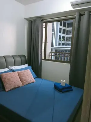 a bedroom with a blue bed with a window at Francheska Suite near Mall of Asia in Manila