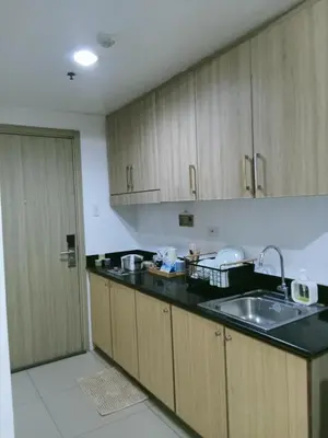 a kitchen with wooden cabinets and a sink and a door at Francheska Suite near Mall of Asia in Manila