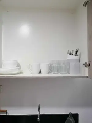 a shelf with plates and glasses on a kitchen counter at Gorgeous 1BR Condo Unit near MOA and Manila Int'l Airport in Manila