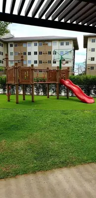 a playground with a red slide in the grass at AA Cozy Comfort in Nuvali in Calamba