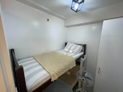 a small bedroom with two beds and a fan at AA Cozy Comfort in Nuvali in Calamba