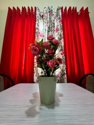 a vase of roses sitting on a table with red curtains at Las Asturias in Balibago