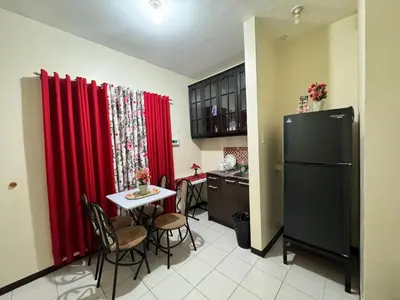a kitchen with red curtains and a table and a refrigerator at Las Asturias in Balibago