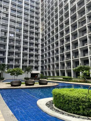 a large apartment building with a pool in front of it at Cozy Vibes near MOA & NAIA AIRPORT with NETFLIX,MINIVIDEOKE,BOARDGAMES-DUXE6 in Manila