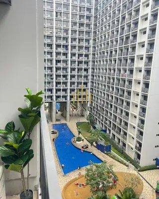 a view of a large apartment building with a swimming pool at Cozy Vibes near MOA & NAIA AIRPORT with NETFLIX,MINIVIDEOKE,BOARDGAMES-DUXE6 in Manila
