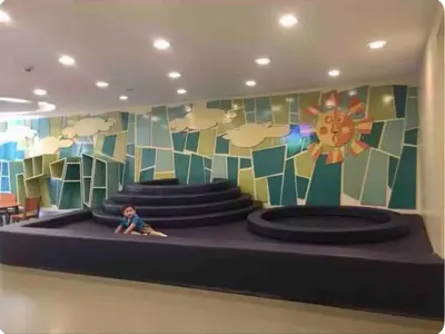 a child sitting on a stage in a room with a mural at Morgan Suites Executive Residences 2 in Manila