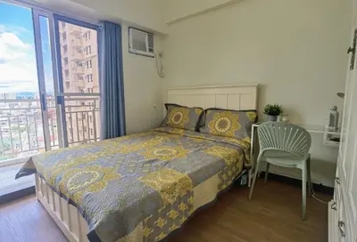 a bedroom with a bed and a table and a window at pasig city resort condo in Manila