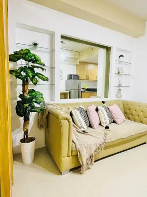 a yellow couch in a living room with a plant at Shell Residences Condotel by Aiza in Manila