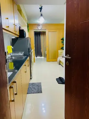 a kitchen with wooden cabinets and a white tile floor at Shell Residences Condotel by Aiza in Manila