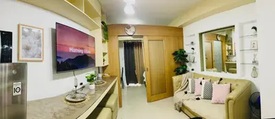 a living room with a couch and a tv in a room at Shell Residences Condotel by Aiza in Manila