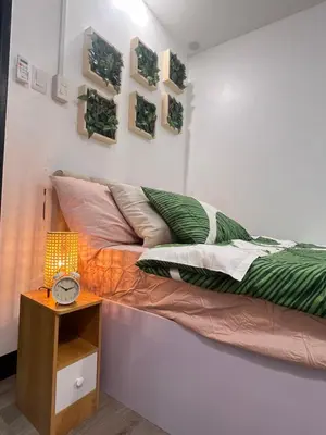 a bed in a room with a clock on a table at Aesthetic 2BR Penthouse near NAIA with Pool in Manila