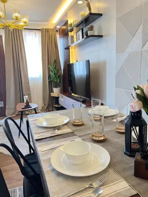 a dining room table with plates and glasses on it at Aesthetic 2BR Penthouse near NAIA with Pool in Manila