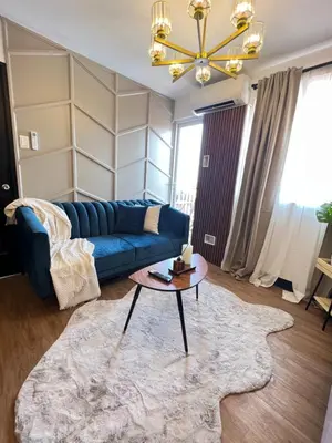 a living room with a blue couch and a table at Aesthetic 2BR Penthouse near NAIA with Pool in Manila