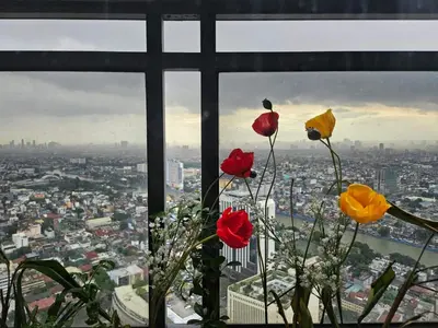 three flowers in a window with a view of a city at Room with stunning view in Makati in Manila