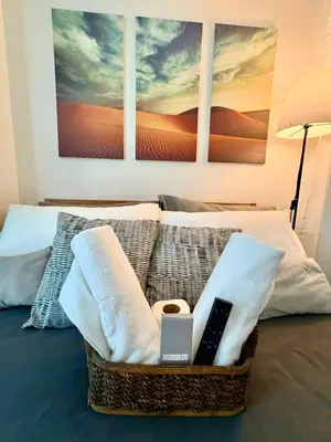 a basket with towels and a remote control on a bed at Bahay-Bahayan in Manila