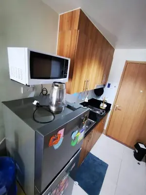a kitchen with a microwave and a black refrigerator at Aldo shore 3 tower 2 mall of Asia in Manila