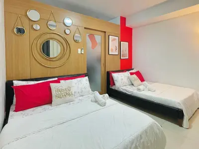 two beds in a room with red and white at Shell Residences Mall of Asia FAMILY ROOM in Manila