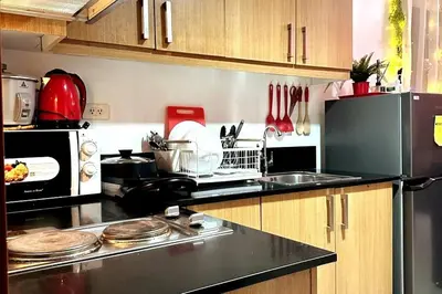 a kitchen with a black counter top and a refrigerator at Shell Residences Mall of Asia FAMILY ROOM in Manila