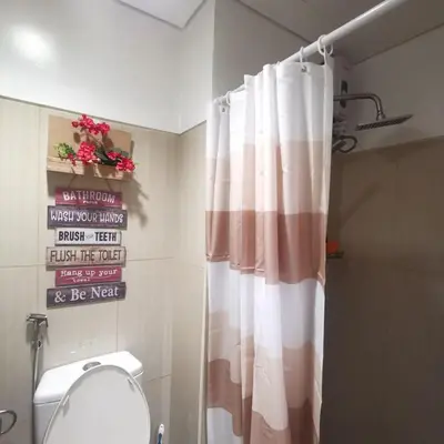 a bathroom with a shower curtain and a toilet at Shell Residences Mall of Asia FAMILY ROOM in Manila