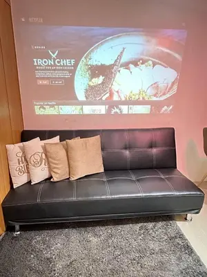 a black leather couch in a room with a poster at Shell Residences Mall of Asia FAMILY ROOM in Manila