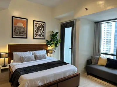 a bedroom with a bed and a couch and a window at Studio in Greenbelt with Wifi, Pool and Gym in Manila