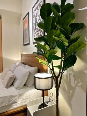 a bedroom with a bed and a lamp and a tree at Studio in Greenbelt with Wifi, Pool and Gym in Manila