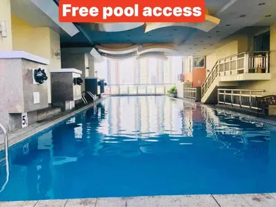 a swimming pool in a hotel room with blue water at Birch Tower a4 front of Robinson Mla FREEpool in Manila