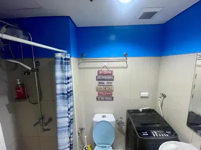 a bathroom with a toilet and a blue wall at MOA Shell Residences - Big Balcony Facing Pool in Manila