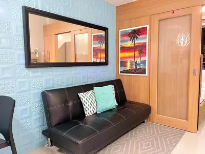 a black leather couch in a room with a mirror at MOA Shell Residences - Big Balcony Facing Pool in Manila
