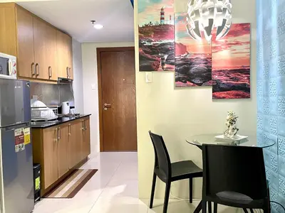 a kitchen with a table and chairs and a refrigerator at MOA Shell Residences - Big Balcony Facing Pool in Manila