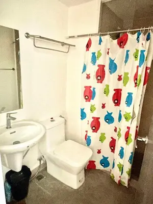 a bathroom with a toilet and a sink and a shower curtain at The Rise Makati in Manila